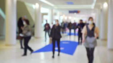 İş merkezinin içindeki büyük, parlak bir salondaki insanlar. Geçmişi bulanık.