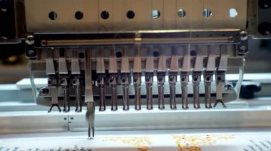 Çalışan bir endüstriyel nakış makinesi fabrikaya bir model uygular. Yakın plan.
