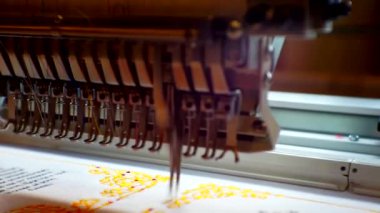 Çalışan bir endüstriyel nakış makinesi fabrikaya bir model uygular. Yakın plan.