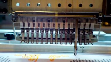 Çalışan bir endüstriyel nakış makinesi fabrikaya bir model uygular. Yakın plan.