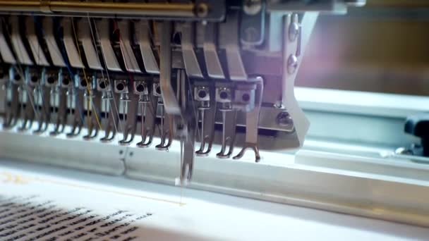 Uma máquina de bordar industrial de trabalho aplica um padrão para o fabric.close-up — Vídeo de Stock