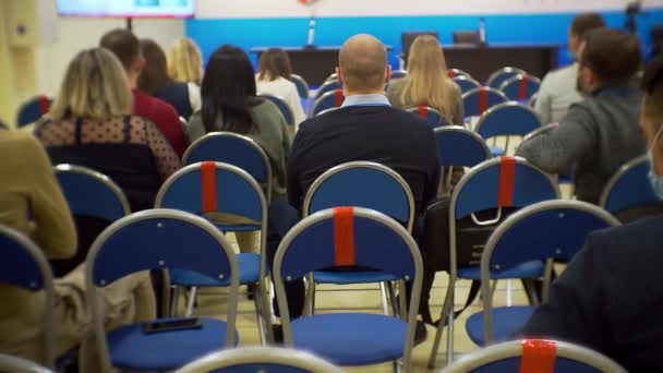 Pessoas irreconhecíveis estão sentadas na audiência do salão ouvindo a apresentação — Vídeo de Stock