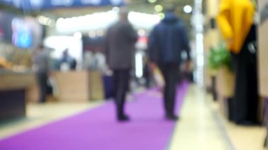 Büyük, parlak bir salonda tanınmayan insanların bulanık siluetleri..