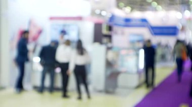 Büyük, parlak bir salonda, tanınmayan modern insanların bulanık siluetleri..