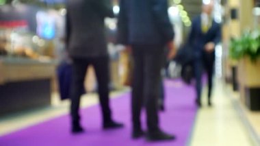 Büyük, parlak bir alışveriş merkezinde tanınmayan insanların bulanık siluetleri..
