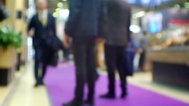 Büyük, parlak bir alışveriş merkezinde tanınmayan insanların bulanık siluetleri..