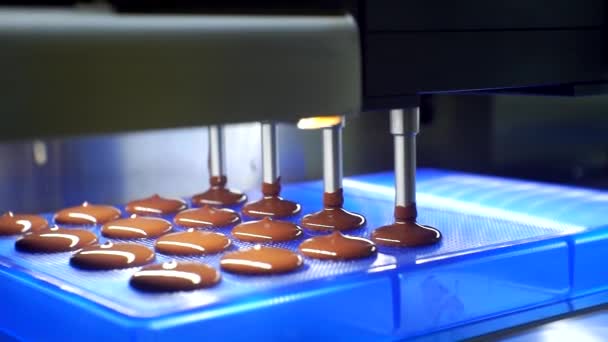 Σύγχρονο εξοπλισμό εργασίας τροφίμων. παραγωγή σοκολάτας.τεχνολογική διαδικασία. η υγρή μάζα σοκολάτας χύνεται από το μηχάνημα. κοντινό πλάνο — Αρχείο Βίντεο