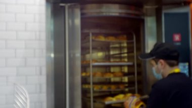 İş teması üzerine bulanık odaklanmış video. Modern küçük işletme. Tanınmayan biri fırından çörek tepsisi çıkarır.