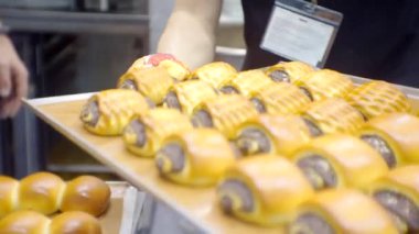 İş teması üzerine bulanık odaklanmış video. Modern küçük işletme. Tanınmayan biri fırından çörek tepsisi çıkarır.