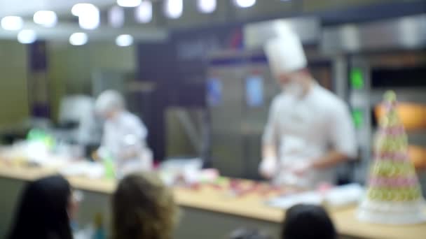 Presentación de productos empresariales modernos. Los chefs dirigen una clase magistral frente a la audiencia reunida. Fondo borroso para un tema culinario o de negocios — Vídeos de Stock