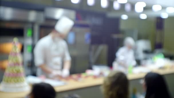 Los chefs actúan frente al público dando una presentación comercial de un producto. Fondo borroso para un tema culinario o de negocios — Vídeos de Stock