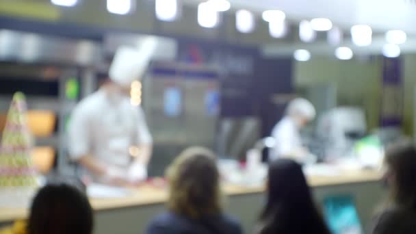 Los chefs actúan frente al público dando una presentación comercial de un producto. Fondo borroso para un tema culinario o de negocios — Vídeos de Stock
