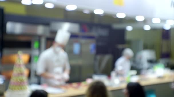 Chefs εκτελέσει μπροστά στο κοινό δίνοντας μια επαγγελματική παρουσίαση ενός προϊόντος. Θολή φόντο για ένα γαστρονομικό ή επιχειρηματικό θέμα — Αρχείο Βίντεο