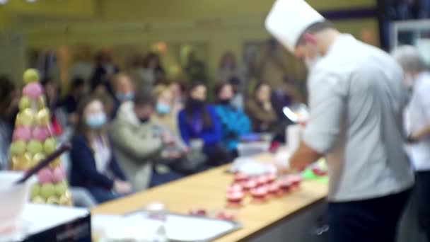 Presentación de productos empresariales modernos. Los chefs dirigen una clase magistral frente a la audiencia reunida. Fondo borroso para un tema culinario o de negocios — Vídeo de stock