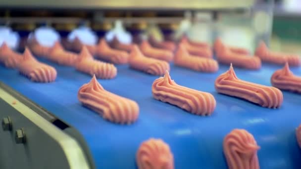 Édességgyártás. mozgó háttér. Egy speciális gép sűrű tejszínből süt süteményeket. kész krémes sütemények mozognak egy szállítószalag mentén. Közelkép. sekély mélységélesség — Stock videók