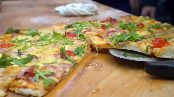 Nowoczesne fast foody. Kawałki świeżej pizzy pokrojone nożem rolkowym na drewnianym stole w pizzerii. Zbliżenie kucharzy układających gorącą pizzę na talerzach — Wideo stockowe