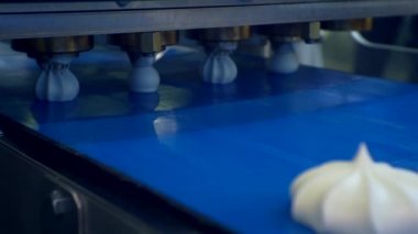 Şekerleme üretimi. hareketli geçmiş. Özel bir makine kalın kremadan pasta yapar. Kremalı kekler konveyör bandı boyunca hareket eder. Yakın plan. Yüzeyin derinliği