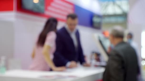 Background on a business theme. blurred silhouettes of businessmen who communicate at the counter at a business meeting in a large bright hall — Stock Video