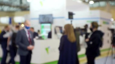 Film ekibi, büyük, parlak bir salonda bir işadamıyla röportaj yapıyor. Eğitim ve iş ile ilgili bulanık bir görüntü.