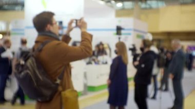 Modern şehir hayatı. Büyük bir alışveriş merkezinde akıllı telefonuyla fotoğraf çeken tanınmayan bir kişinin bulanık silueti. İş konuları üzerine kreensaver ya da arka plan