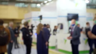 Film ekibi, büyük, parlak bir salonda bir işadamıyla röportaj yapıyor. Eğitim ve iş ile ilgili bulanık bir görüntü.