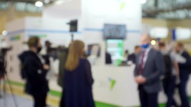 Film ekibi, büyük, parlak bir salonda bir işadamıyla röportaj yapıyor. Eğitim ve iş ile ilgili bulanık bir görüntü.