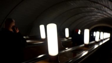 Yeraltı metro konsepti. Metrodaki tanınmayan insanlar yürüyen merdivene biniyor. Bir sürü insan yaşam tarzı videosunu bulanıklaştırdı. İnsanlar aşağı inip metro asansörüne çıkıyorlar.