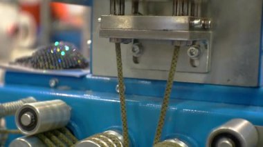 Modern teknolojiler. İş geçmişi. Teknolojik süreç. Tekstil ürünleri için bir üretim makinesinin parçası. Makinenin şaftındaki ip yavaşça döner ve geri sarar. Yakın çekim.