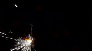 Yılbaşı ve Noel festivali geçmişi. Sparkler parlak bokeh çemberlerinin arka planında parlak bir şekilde yanar. Yakın plan. Sığ alan derinliği