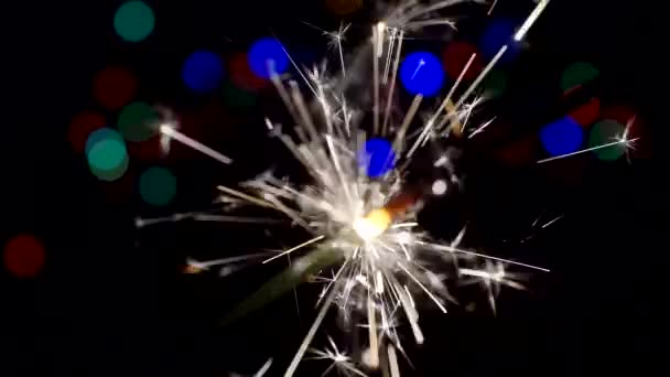 Fondo festivo.Año Nuevo y Christmas.burning sparkler.Bengal vela arde brillantemente sobre un fondo de círculos bokeh brillantes.Close-up.Shallow profundidad de campo — Vídeo de stock