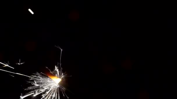 Ano Novo e Natal fundo festivo. Sparkler queima brilhantemente em um contexto de círculos de bokeh brilhantes. Close-up. Profundidade de campo rasa — Vídeo de Stock