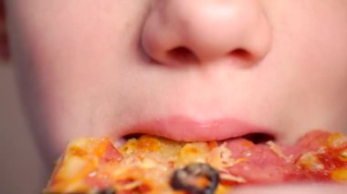 Modern yemek. İştahlı bir çocuk lezzetli bir dilim pizza yer. Yakın plan.