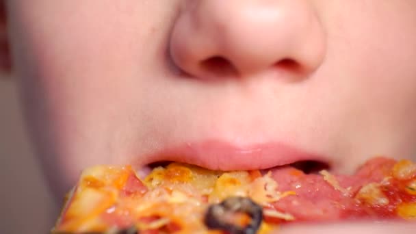 Сучасна їжа. рот, який хлопчик з апетитом їсть шматочок смачної піци. Крупним планом. мала глибина різкості — стокове відео