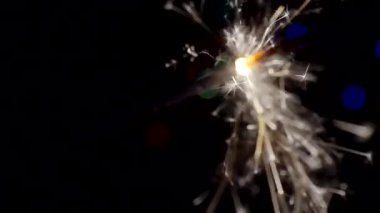 Yılbaşı ve Noel festivali geçmişi. Sparkler parlak bokeh çemberlerinin arka planında parlak bir şekilde yanar. Yakın plan. Sığ alan derinliği