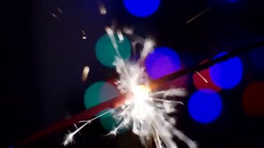 Şenlikli bir arkaplan. Yeni yıl ve Noel. Maytap yakmak, parlak Bokeh çemberlerinin arka planında parlak bir şekilde yanar. Yakın plan.