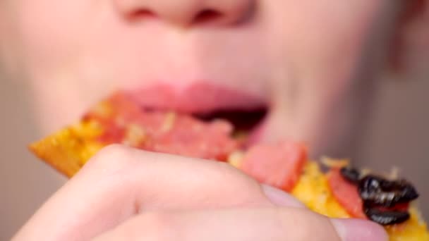 Moderní jídlo.Ústa, že chlapec s chutí k jídlu jí kus chutné pizza.Close-up. — Stock video