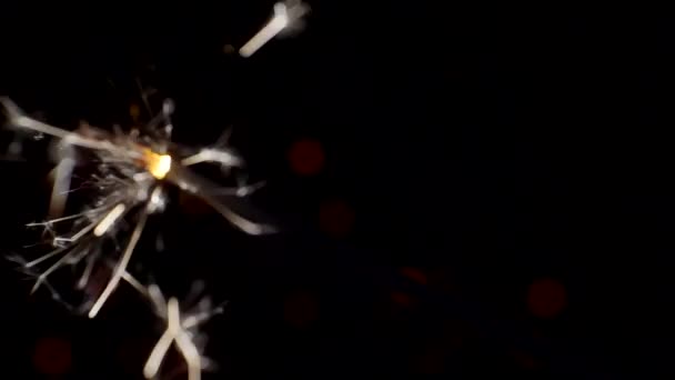 Πρωτοχρονιά και Χριστούγεννα εορταστική φόντο. Sparkler καίει έντονα σε ένα φόντο φωτεινό bokeh κύκλους. Κοντινό πλάνο. Ρηχό βάθος πεδίου — Αρχείο Βίντεο