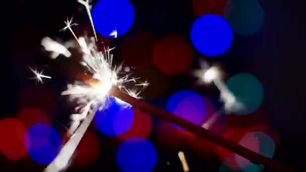 Ano Novo e Natal fundo festivo. Sparkler queima brilhantemente em um contexto de círculos de bokeh brilhantes. Close-up. Profundidade de campo rasa — Vídeo de Stock