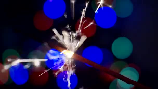 Latar belakang Tahun Baru dan Natal. Sparkler membakar terang terhadap latar belakang bokeh lingkaran terang. Close-up. Kedalaman field yang dangkal — Stok Video