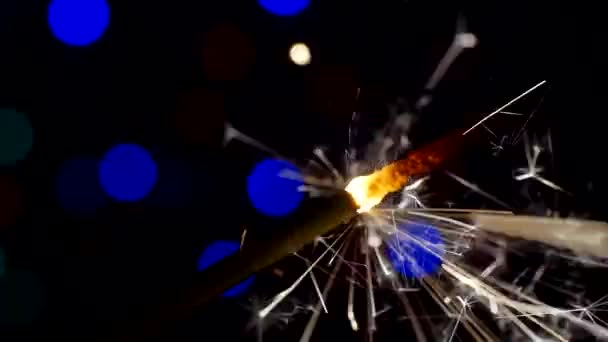 Ano Novo e Natal fundo festivo. Sparkler queima brilhantemente em um contexto de círculos de bokeh brilhantes. Close-up. Profundidade de campo rasa — Vídeo de Stock