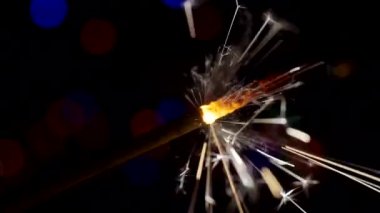 Yılbaşı ve Noel festivali geçmişi. Sparkler parlak bokeh çemberlerinin arka planında parlak bir şekilde yanar. Yakın plan. Sığ alan derinliği