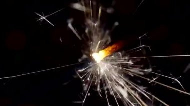 Yılbaşı ve Noel festivali geçmişi. Sparkler parlak bokeh çemberlerinin arka planında parlak bir şekilde yanar. Yakın plan. Sığ alan derinliği