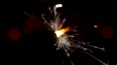 Şenlikli bir arkaplan. Yeni yıl ve Noel. Maytap yakmak, parlak Bokeh çemberlerinin arka planında parlak bir şekilde yanar. Yakın plan.