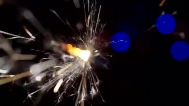 Yılbaşı ve Noel festivali geçmişi. Sparkler parlak bokeh çemberlerinin arka planında parlak bir şekilde yanar. Yakın plan. Sığ alan derinliği