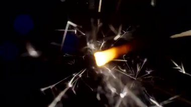Şenlikli bir arkaplan. Yeni yıl ve Noel. Maytap yakmak, parlak Bokeh çemberlerinin arka planında parlak bir şekilde yanar. Yakın plan.