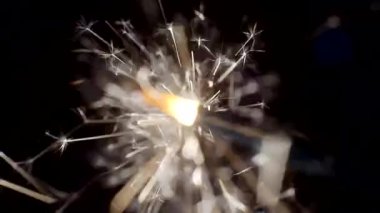 Yılbaşı ve Noel festivali geçmişi. Sparkler parlak bokeh çemberlerinin arka planında parlak bir şekilde yanar. Yakın plan. Sığ alan derinliği