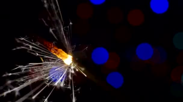 Festlicher Hintergrund. Silvester und Weihnachts.brennende Wunderkerze. Bengalische Kerze brennt hell vor einem Hintergrund heller Bokeh-Kreise. Großaufnahme. Flache Schärfentiefe — Stockvideo