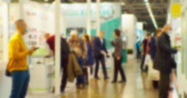 Büyük, parlak bir salonda, tanınmayan modern insanların bulanık siluetleri. Soyut iş geçmişi