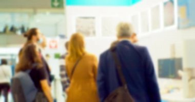 İş merkezinin içindeki büyük, parlak bir salonda birçok insan var. Bir iş temasının bulanık arkaplanı.