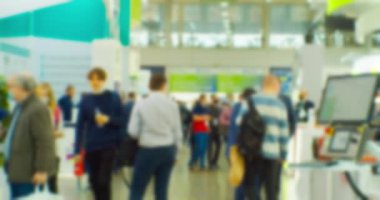 Büyük, parlak bir salonda, tanınmayan modern insanların bulanık siluetleri. Soyut iş geçmişi